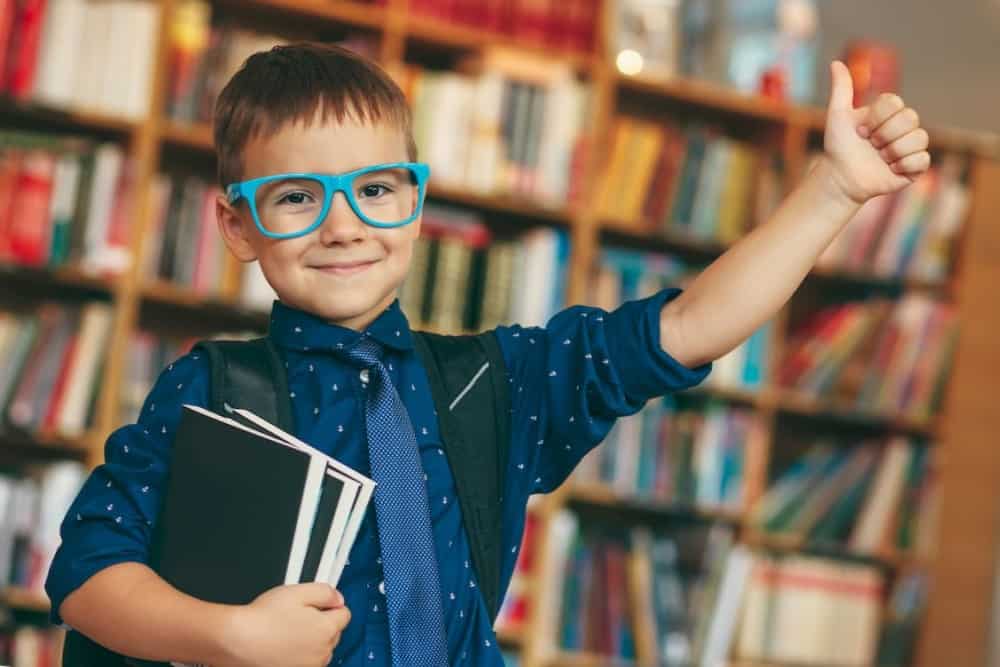 A small boy is showing thumbs up in the library 